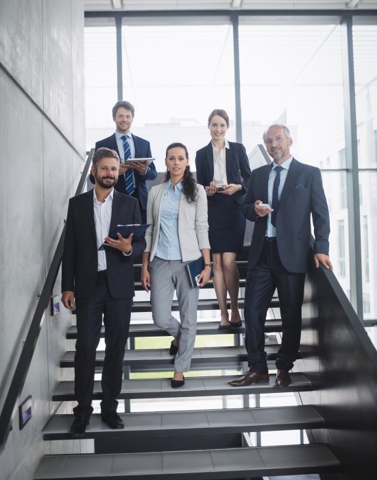 Portrait of confident businesspeople standing on staircase in office Portrait of confident businesspeople standing on staircase in office